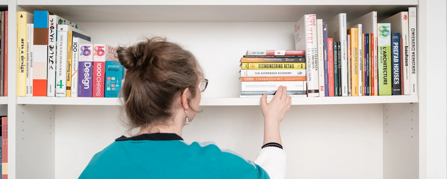 elisa-servais-services Elisa picking a book on a shelf